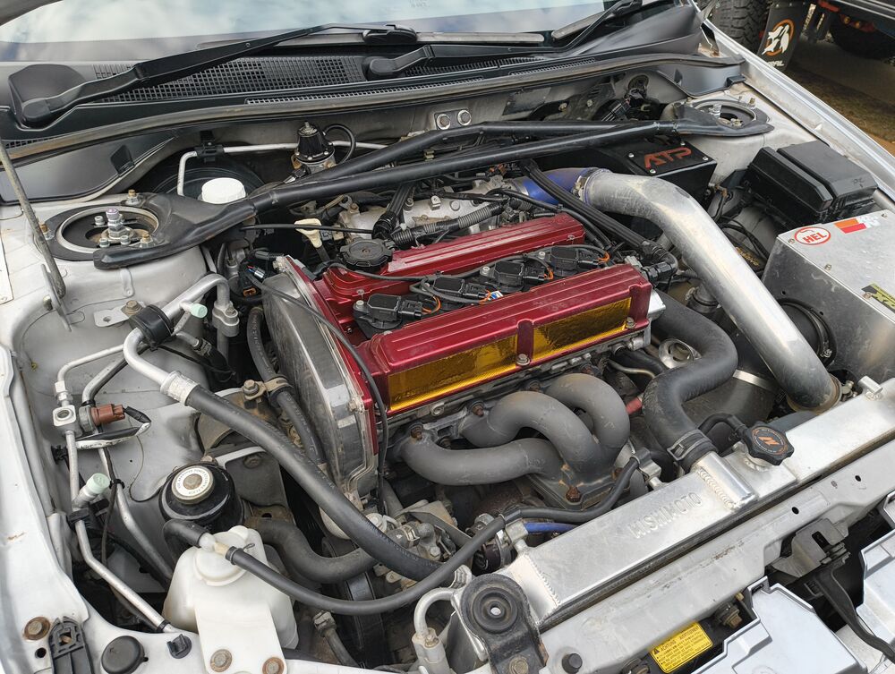 Engine bay overview — 4G63T with red rocker cover, ATP turbo bracket, intercooler piping